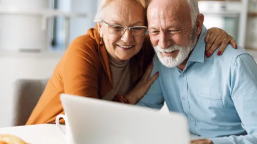 Embraced senior couple using laptop at home