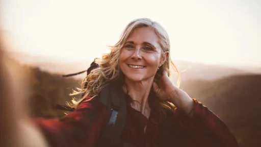 Cheerful senior woman on hiking trip on the mountains taking a selfie on mountain top