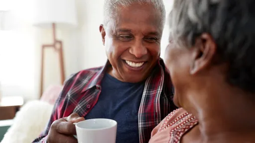 Senior Couple Sitting On Sofa At Home Relaxing With Hot Drink