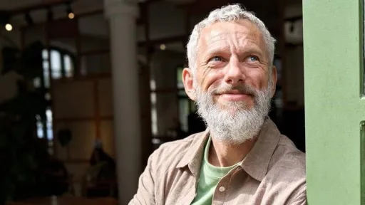 Senior entreprenuer smiling leaning against opening of business