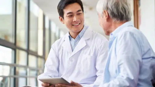 Asian physician conversing with elderly man
